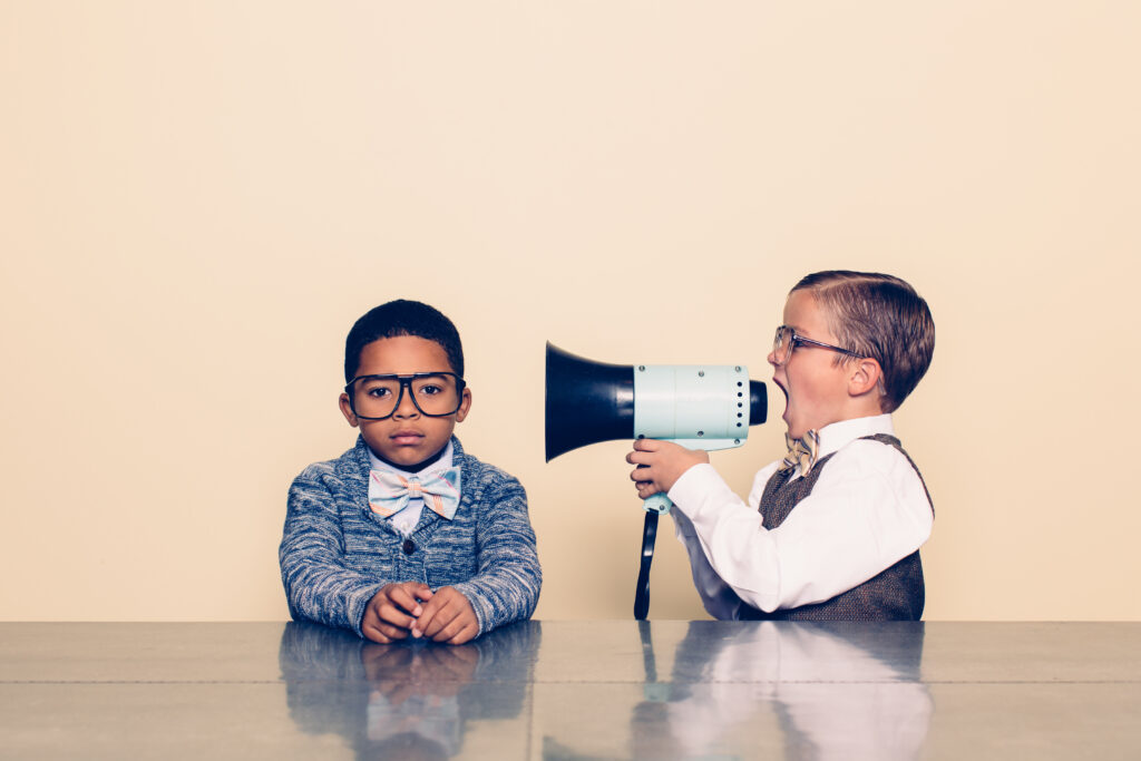 Young boy screaming at another boy through megaphone